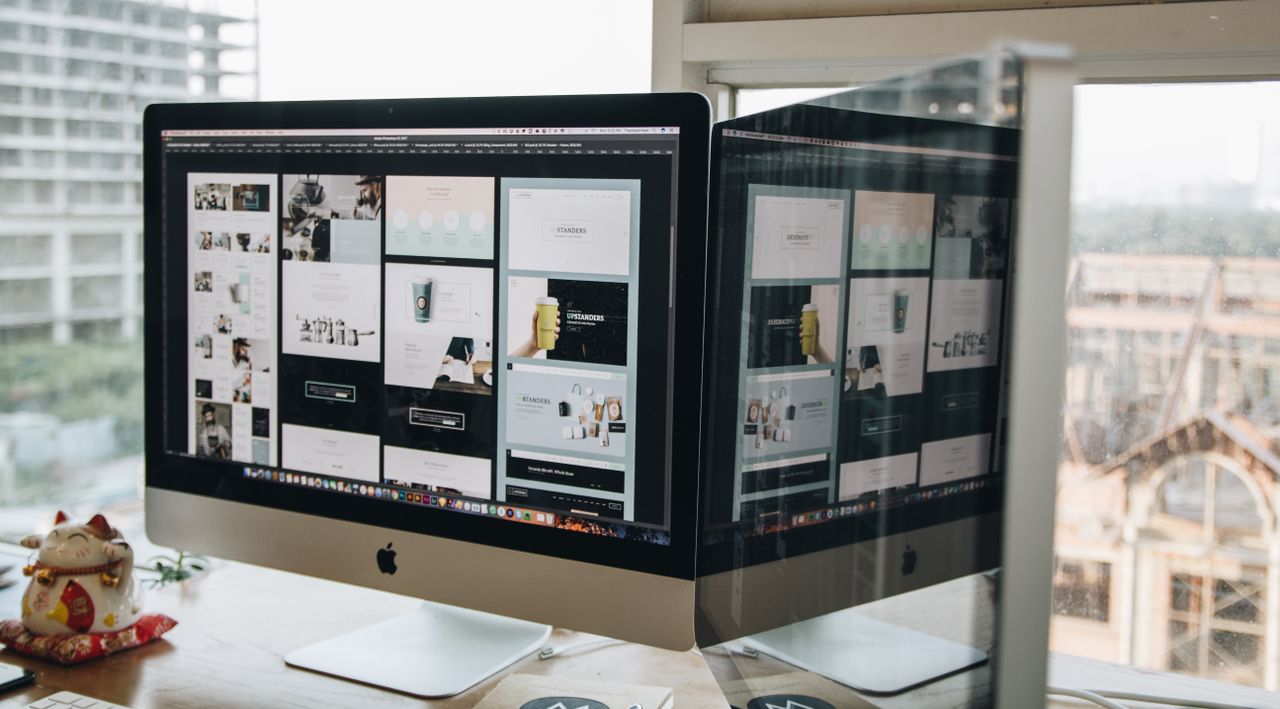 about-01 Dual monitors on a desk, showcasing web design in a modern office setting.